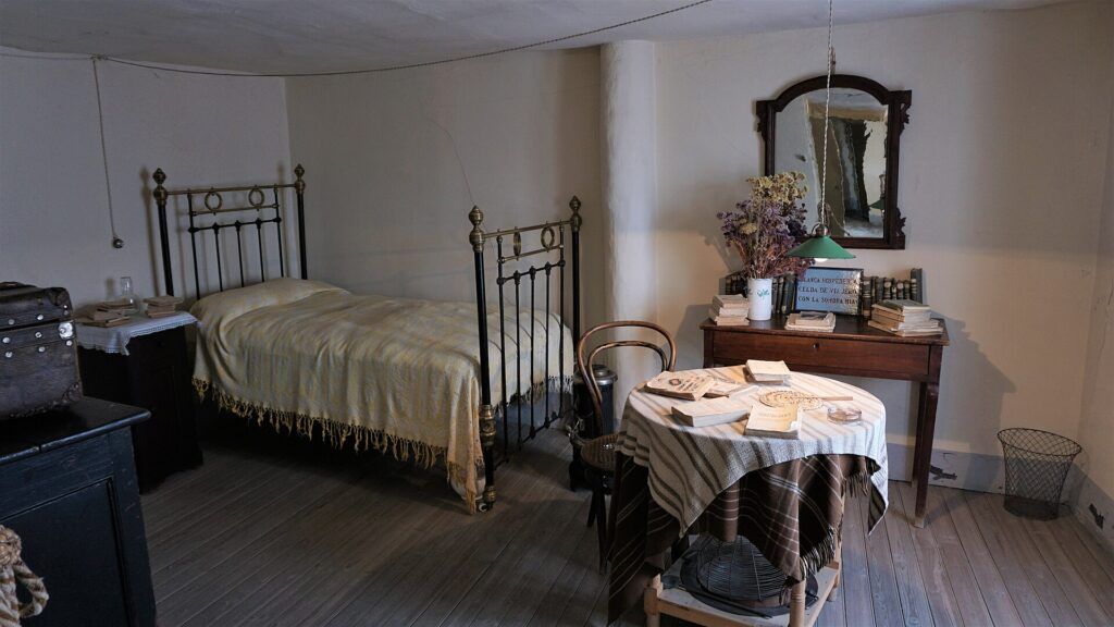 Habitación de Antonio Machado en la casa-museo de Segovia, con la cama de hierro, la mesa camilla y el escritorio con sus libros