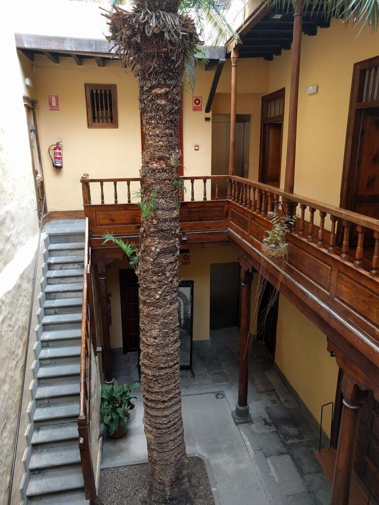 Patio canario de la Casa-Museo Pérez Galdós en Las Palmas de Gran Canaria, con galería de madera y una palmera en el centro