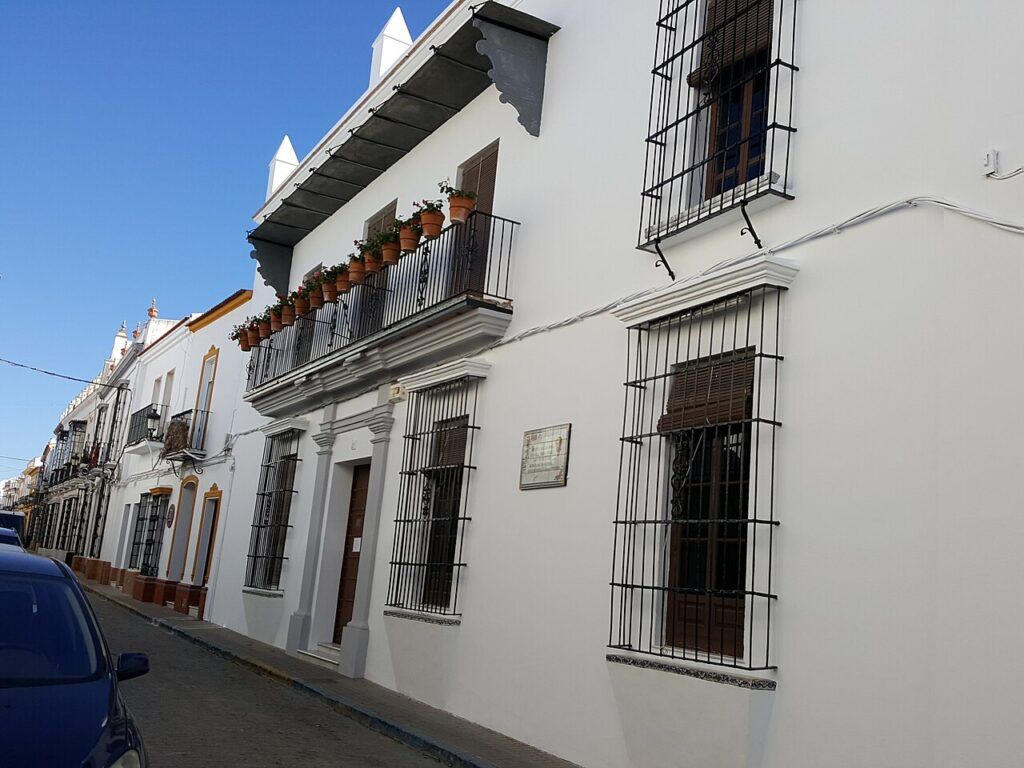 Fachada blanca de la Casa-Museo Zenobia y Juan Ramón Jiménez en Moguer, con rejas en las ventanas y un balcón con macetas