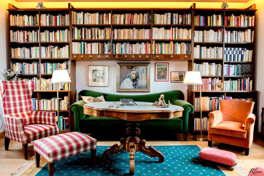 Biblioteca de la primera planta de la torre en la casa familiar de Carmen Martín Gaite en El Boalo, con un sofá verde, butacas y un retrato en la pared