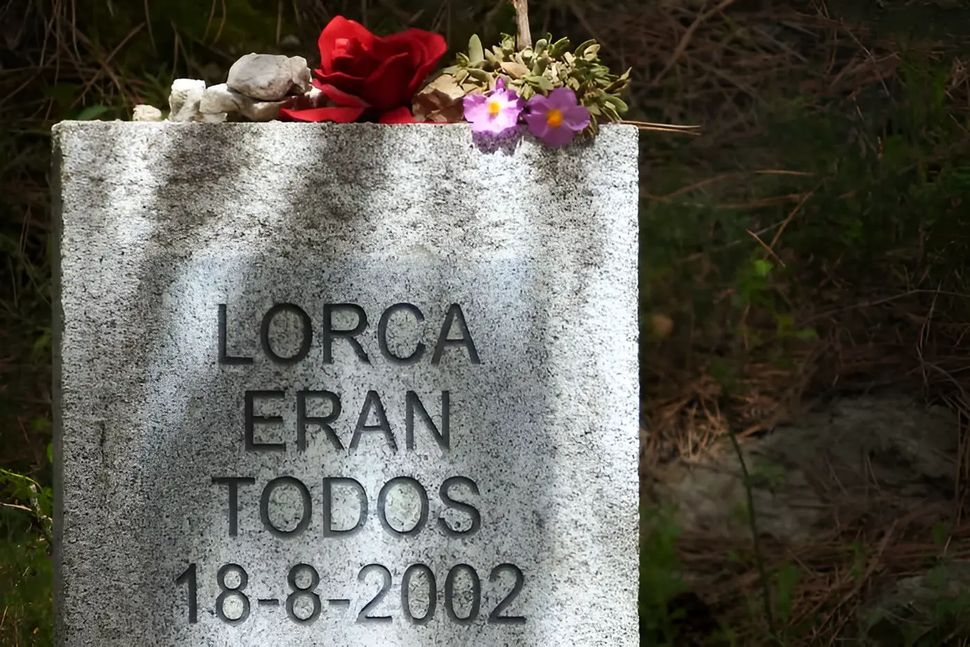 Monolito de piedra con la inscripción «Lorca eran todos 18-8-2002», con flores y piedras dejadas en su memoria, entre Víznar y Alfacar